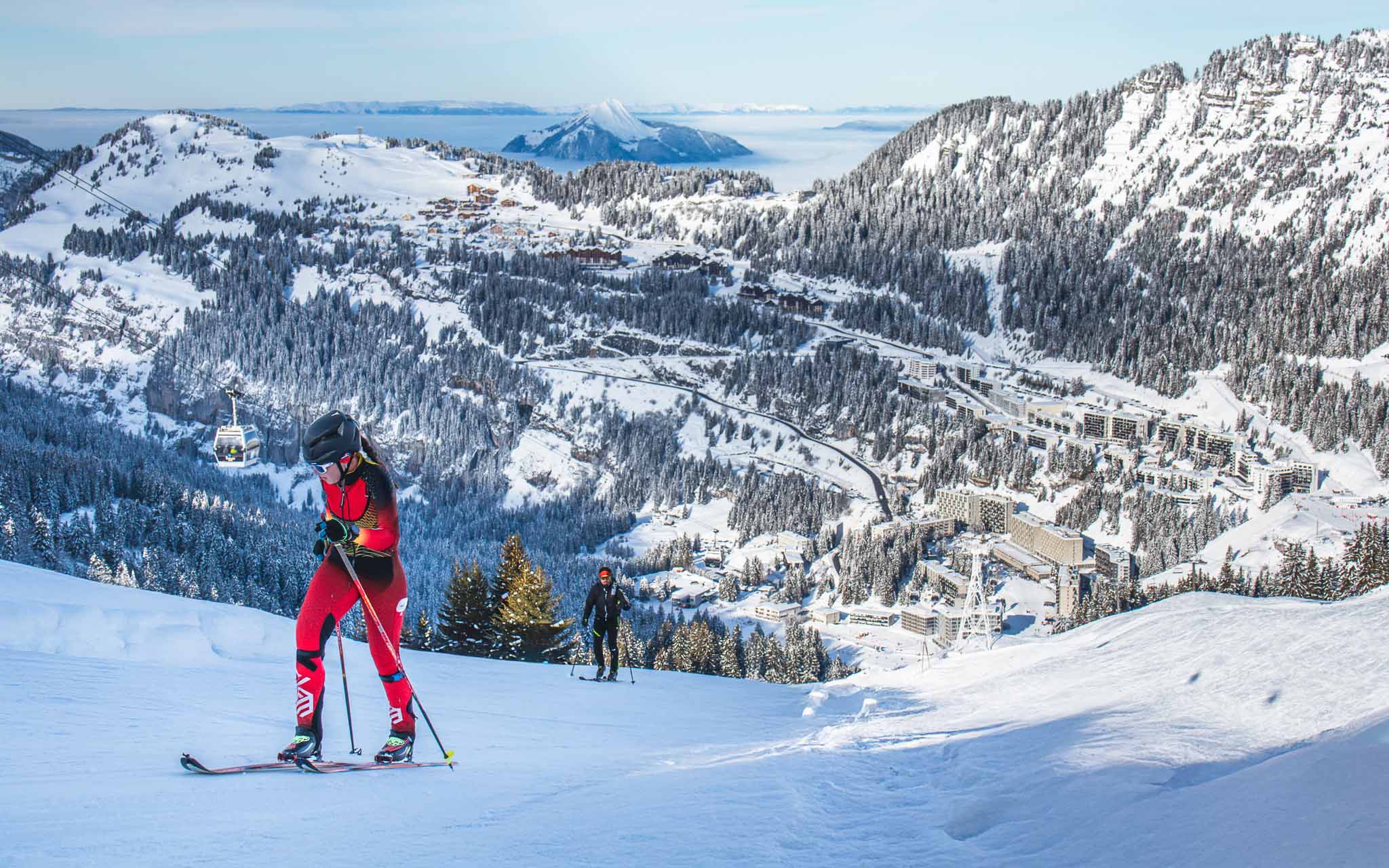 Des skieurs de randonnée montent un itinéraire enneigé, avec la station de ski de Flaine visible en contrebas.